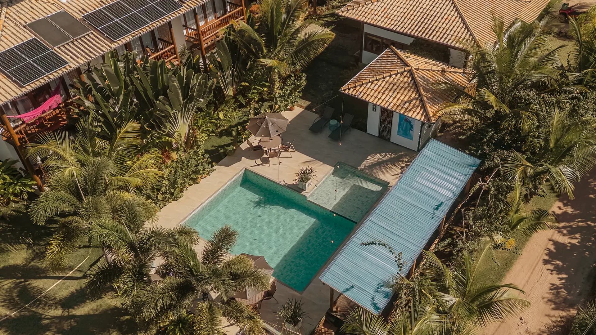 Vista aérea da pousada Taipu Bay cercada por vegetação tropical, com piscina ao centro.